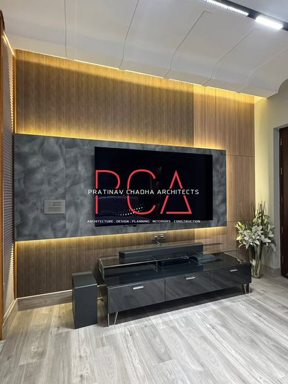 The TV and entertainment unit in the son's room features a combination of louvered wood panels and a stone-patterned surface. Backlighting adds depth and accentuates the different textures, creating a focal point that is both stylish and functional.