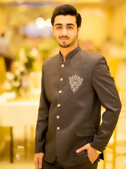 A confident portrait of the groom. His hair is perfectly styled, and his makeup is flawless, ready for the camera.