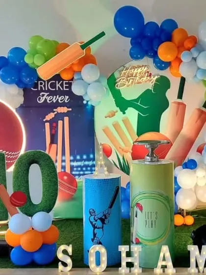 A dynamic cricket-themed birthday party with cutouts of famous cricketers, a large cricket ball prop, and a 'Cricket Fever' backdrop.