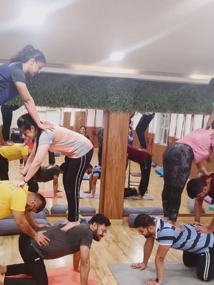 Two groups of students working together to build human pyramids. This is a fun and challenging way to practice acro yoga.