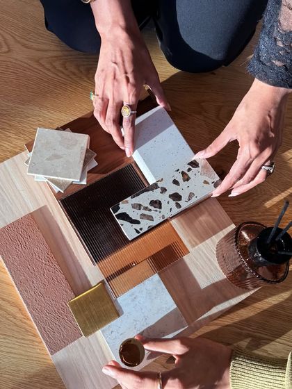 The process of creating a mood board is collaborative and tactile. Here, hands arrange samples of terrazzo, wood, and glass, demonstrating the hands-on approach I take to material selection.