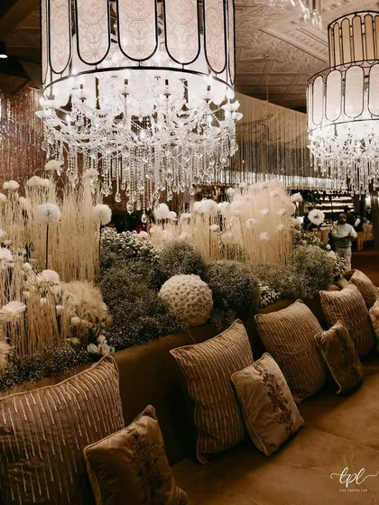 A comfortable lounge area with plush velvet cushions, set amidst a forest of white and beige dried florals. The textures and neutral palette create a sophisticated and modern atmosphere.
