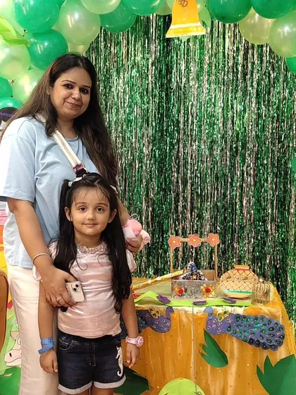 A mother and daughter pose happily at our Janmashtami event. The detailed decorations provide a beautiful setting for family photos.