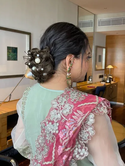 A different angle of the pearl-adorned messy bun, showing its volume and intricate twists. It's a perfect hairstyle for a sangeet or engagement party.