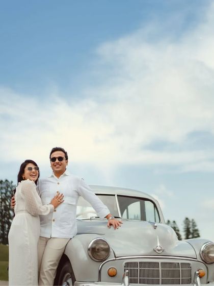 A classic, elegant portrait of a couple with a vintage car against a bright blue sky in Kashmir. This shot has a timeless, celebratory feel, perfect for an anniversary lookback.