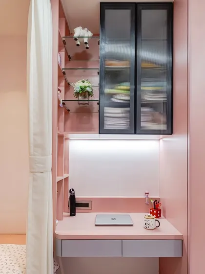 Designed for a chic pastel room, this compact desk is perfect for smaller spaces. It features integrated drawers, power access, and is connected to a vertical shelving unit with both open and closed storage for a tidy look.