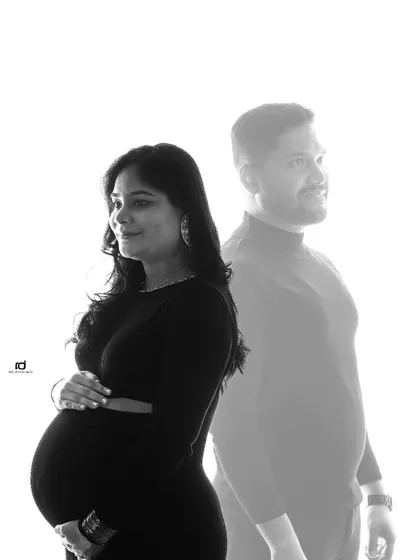 A creative double-exposure style portrait. This image artistically places the mom-to-be in the foreground, with her partner a gentle presence behind her, symbolizing his support.