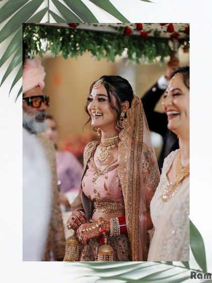 A happy, candid moment of the bride laughing under a floral canopy, surrounded by her family, capturing the joy of the day.