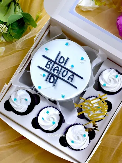 A simple and sweet bento set for a sibling, with 'Didi Bada' written on the cake in a tic-tac-toe design. The minimalist black and white theme is carried over to the accompanying cupcakes.