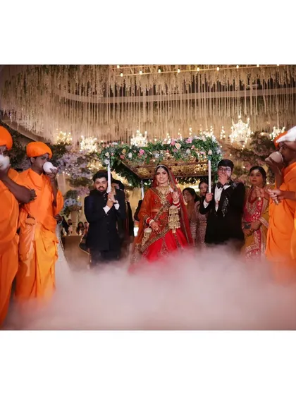 A sacred moment as the bride makes her entrance under a phoolon ki chadar, surrounded by priests blowing conch shells. This is tradition and emotion captured in one frame.