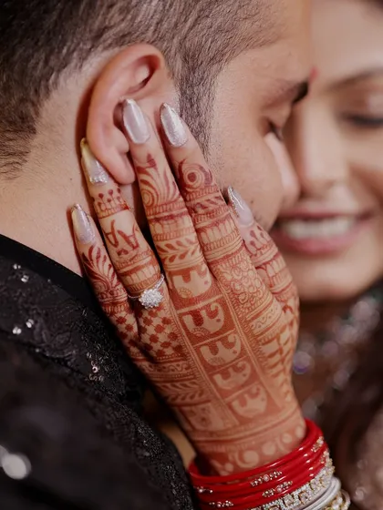 A detail shot focusing on the bride's intricate mehendi design and her engagement ring. Capturing these small but significant details is a key part of our wedding coverage.