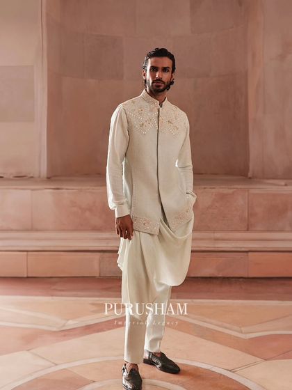 This full-length view shows how the draped kurta and embroidered jacket come together. It is an ensemble designed to shape a modern man, blending tradition with a forward-thinking approach to style.