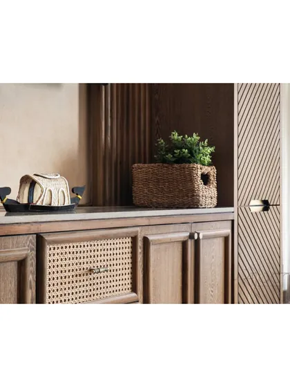 A close-up detail of the TV console, emphasizing the craftsmanship and the blend of wood, cane, and basket-weave textures.