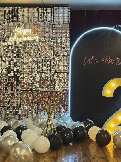 We love creating chic and glamorous setups for anniversaries. This dual backdrop features a stunning silver shimmer wall and a sleek black arch, complemented by marquee numbers, making it the perfect photo spot for a 25th anniversary celebration.