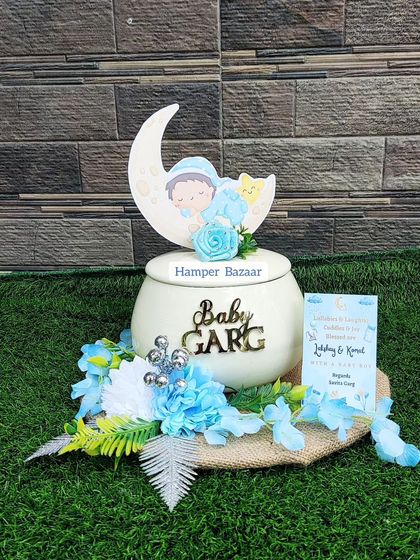 A unique 'handi' style hamper for a baby boy announcement, placed on a rustic jute base.