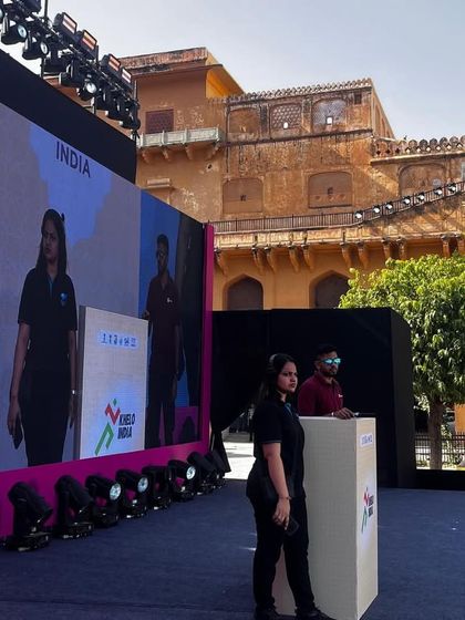 A team member stands by during a rehearsal for the Khelo India University Games launch, ensuring the stage is ready for the next segment.