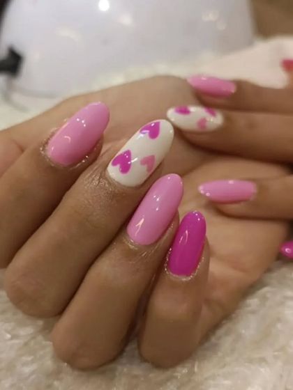 Spread the love with this adorable heart-themed manicure. The design alternates between solid pink nails and a white accent nail covered in small pink hearts, perfect for a sweet and romantic vibe.