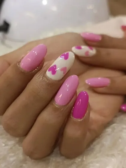 Spread the love with this adorable heart-themed manicure. The design alternates between solid pink nails and a white accent nail covered in small pink hearts, perfect for a sweet and romantic vibe.