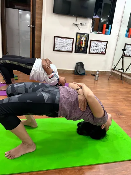 Two students practicing Grivasana side-by-side. This image shows the focus and strength required to hold the pose, which is highly effective for improving posture and preventing thyroid issues.