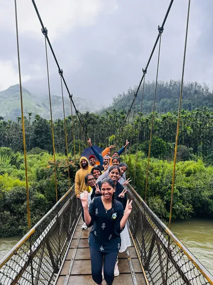 The journey is just as exciting as the destination. A happy group crosses a suspension bridge during a monsoon trek in the Kudremukha National Park, a perfect example of the adventures I plan.