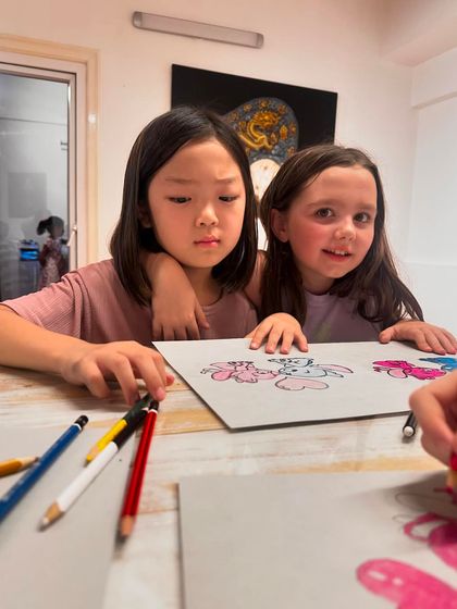 Two friends share a moment while working on their character drawings. Art class is a great place to bond and make new friends.