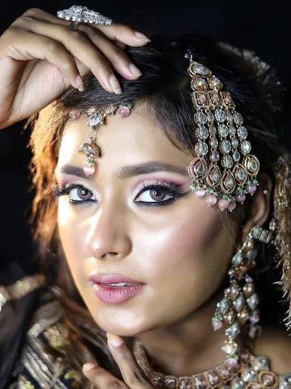 A close-up of the modern bridal makeup, showing the delicate winged liner and the intricate passa on the side of her head. I teach both traditional and contemporary jewelry placement.