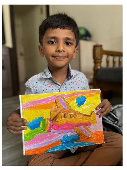 A first-grade student displays his colourful airplane drawing against a bright, blended sky. We learn techniques to make our drawings dynamic and full of energy.
