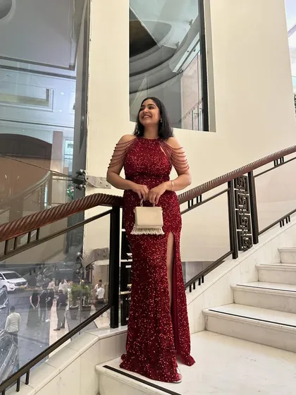 Posing on the staircase at a wedding reception. This red gown is a perfect example of a wedding guest outfit that is show-stopping yet elegant, without upstaging the bride.