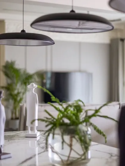 A detail shot of the dining table, with sculptural decor and a view of the living room in the background. The open-plan design creates a sense of connection and flow.