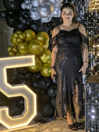 This setup includes a large light-up marquee number '15' next to the black and gold balloon arrangement and sequin wall.