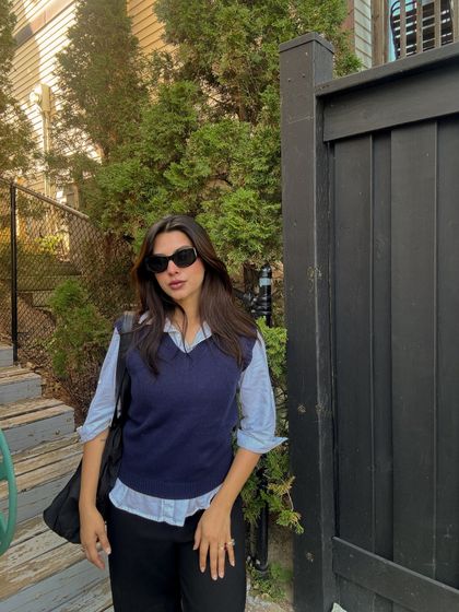 A classic street style pose, showing off the layered sweater vest look.