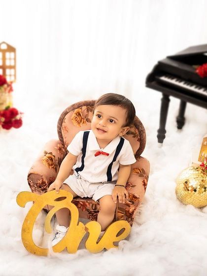 Posing with the 'One' sign to mark his first birthday. This classic shot is a must-have for any first birthday photoshoot.