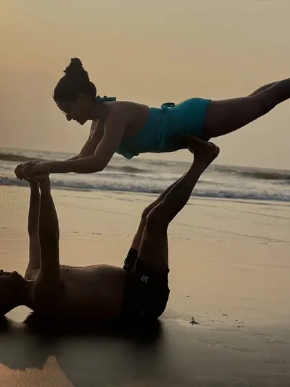 Partner yoga is about finding balance together. This acro-yoga pose, often called "Flying Whale" or "Bird," requires trust, strength, and a bit of playfulness. It’s a beautiful way to connect and support each other, set against the calming backdrop of the ocean.