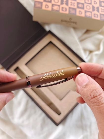 A close-up of the personalized Sheaffer pen, showing the detail of the hand-lettered name 'Abhishek'.