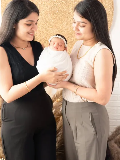 A new baby brings so much joy to the entire family. Here, the baby is being lovingly held by her mother and aunt, showing how love multiplies.