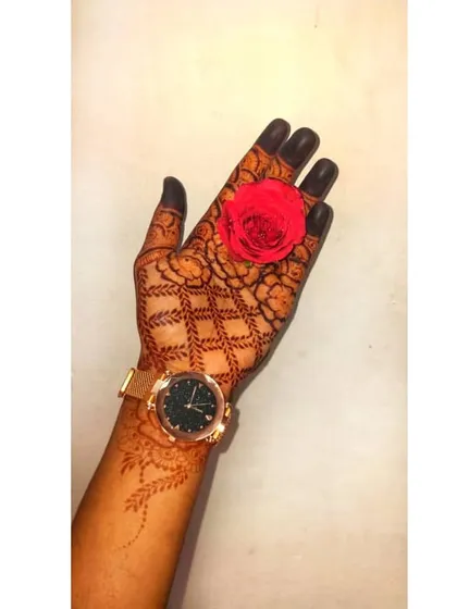 A creative shot of a palm with a jaal (net) pattern, holding a single red rose.