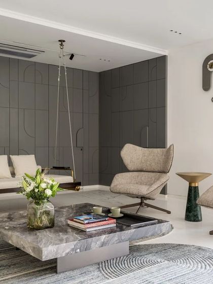 The formal living area at Park West is a study in serene elegance. I paired a minimalist indoor swing with sculptural armchairs and a monolithic stone coffee table to create a space that feels both sophisticated and welcoming. The paneled grey wall conceals storage, maintaining a clean and uncluttered aesthetic.