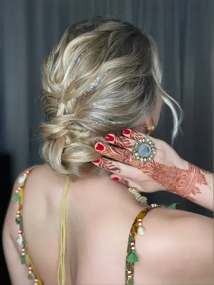 Another angle of the messy bun, showcasing the texture and the way it complements the henna-adorned hand.