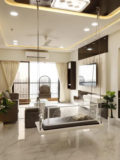 A clear acrylic indoor swing adds a touch of modern elegance without visually cluttering this spacious Malad living room. The design maintains an open feel, complemented by the marble flooring and sophisticated ceiling cove lighting.