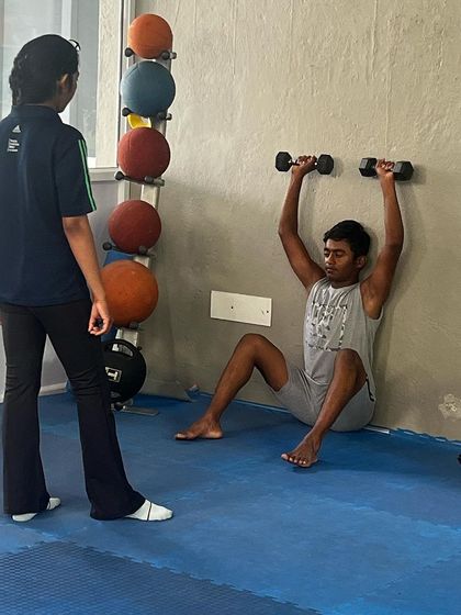 Our sports science team is dedicated to the health of our players. Here, a physiotherapist works with an athlete on a shoulder stabilization exercise using dumbbells.