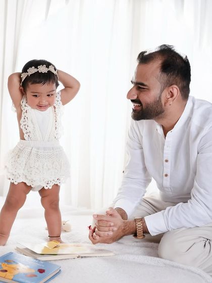 A story in a single frame. The little girl's playful pose and her father's loving gaze create a picture full of personality and warmth.