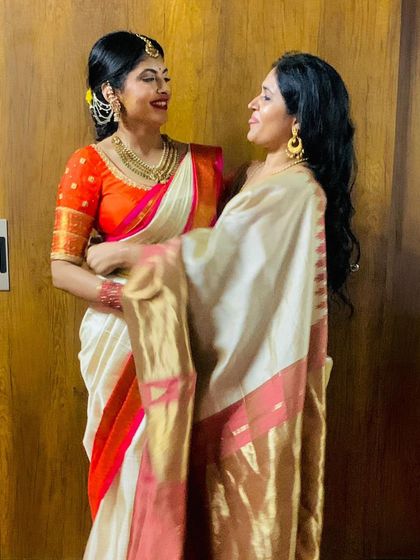 A heartwarming photo of two sisters. Neha wears a custom orange blouse with her white and red border saree.