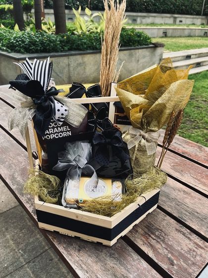 A black, white, and gold themed hamper that showcases a bold and modern styling approach, using contrasting ribbons and metallic accents.