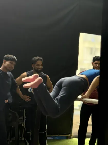 Spotting a student as she works on her back lever. This is a crucial part of the learning process for advanced statics.