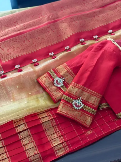 A classic red and gold half-saree set. The blouse sleeves and dupatta border are embellished with Jadau-style pendants and delicate tassels.