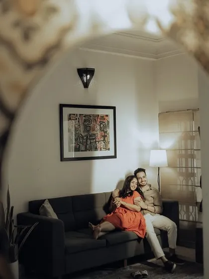 A cozy indoor portrait, viewed through the arch of a decorative mirror. This creative framing adds depth and a sense of peeking into a private, comfortable moment.
