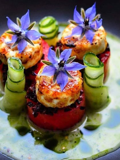 Our chefs are skilled in creating visually stunning dishes. Here, seared halloumi is stacked on roasted tomatoes and garnished with edible borage flowers and cucumber ribbons for an elegant appetizer.