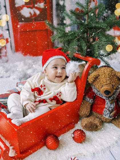 A close-up of the baby girl playing with her Santa hat, full of personality and charm.
