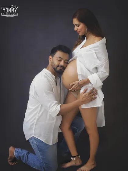 A quiet moment of pure love between expecting parents. This classic studio maternity portrait, with its simple white shirts and jeans, focuses entirely on the connection and anticipation of their little miracle.