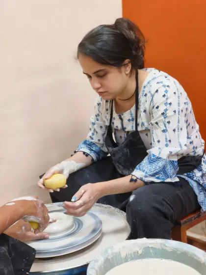 A student carefully refines the rim of her bowl with a sponge. This step ensures the piece is smooth and comfortable to use.